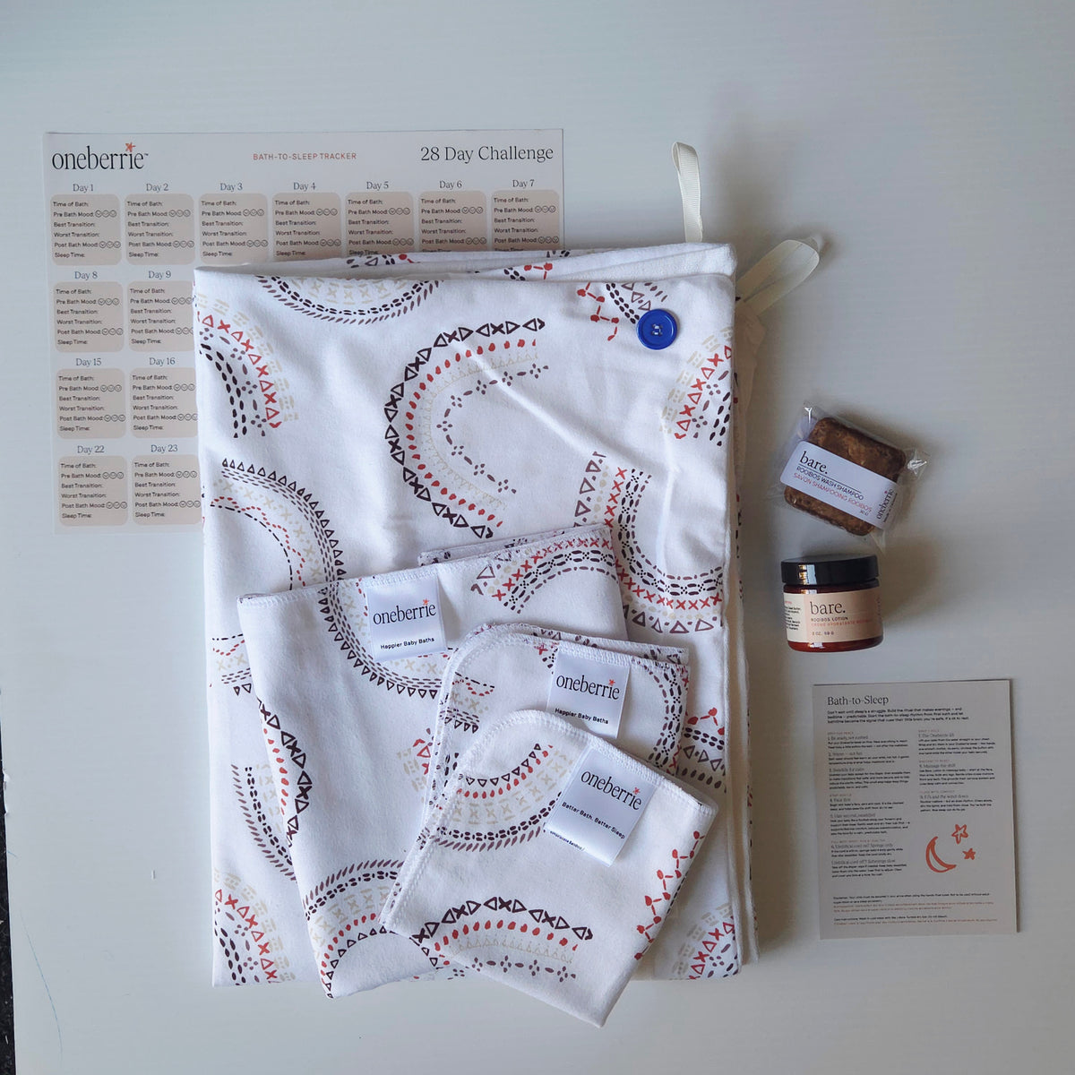 Bath to bed set from Oneberrie on a light grey background. Includes a geometric rainbow pattern on a white flannel with a matching washcloth, a wipe, a 2oz Bare. Lotion, a 30g Bare. Shampoo Wash, a 28 bath challenge tracker adn a bath for sleep Oneberrie method.