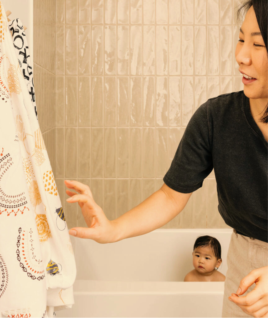 Mom reaching for a Oneberrie towel as her Infant is in the tub