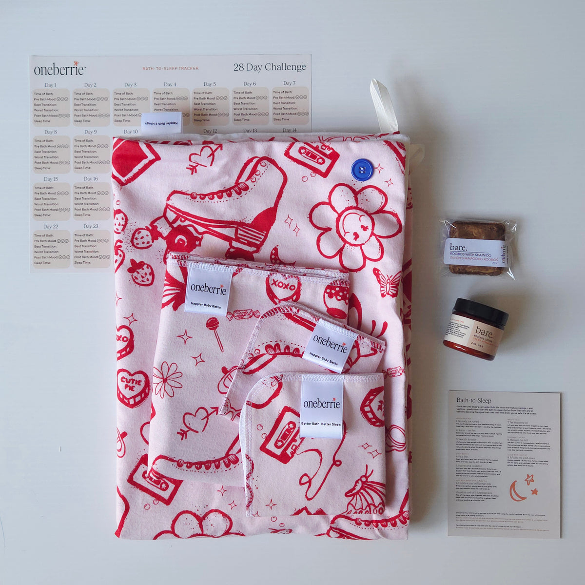 A Bath to bed complete set by OneBerrie, featuring  pink ladies retro pattern with red designs on a pink background, a matching bath swaddle, a washcloth, a 2oz Bare. Lotion, 30g Bare. Shampoo Wash, a 28-day challenge tracker sheet, and an instruction card on a light gray background