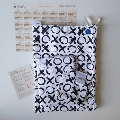 A Bath to Bed Core set by OneBerrie, featuring  Love you More XO black pattern on white background,, a matching bath swaddle, a washcloth, a 28-day challenge tracker sheet, and an instruction card on a light gray background