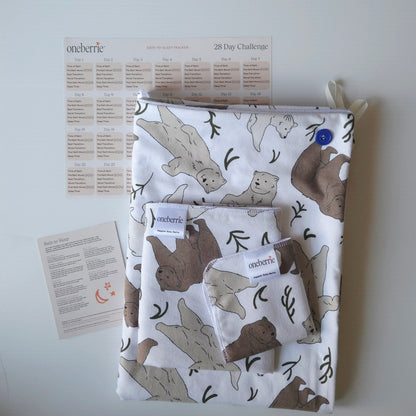 A Bath to Bed Core set by OneBerrie, featuring  Three bears pattern with a grizzly, brown bear and polar bear, a matching bath swaddle, a washcloth, a 28-day challenge tracker sheet, and an instruction card on a light gray background.