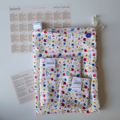 A Bath to Bed set by OneBerrie, featuring  Wild flower colourful pattern on white background, a matching bath swaddle, a washcloth, a 28-day challenge tracker sheet, and an instruction card on a light gray background