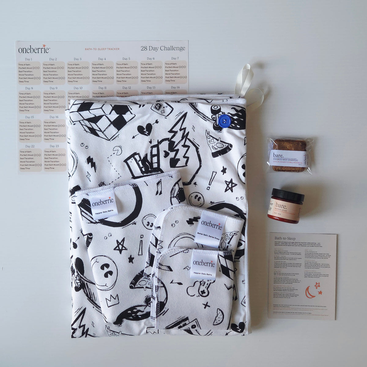 A Bath to Bed Complete set by OneBerrie, featuring  Cool Dudes retro pattern with black designs on a white background, a matching bath swaddle, a washcloth, a cloth wipe and a 2oz Bare. Lotion with a 30g Bare. Shampoo Wash bar, a 28-day challenge tracker sheet, and an instruction card on a light gray background.
