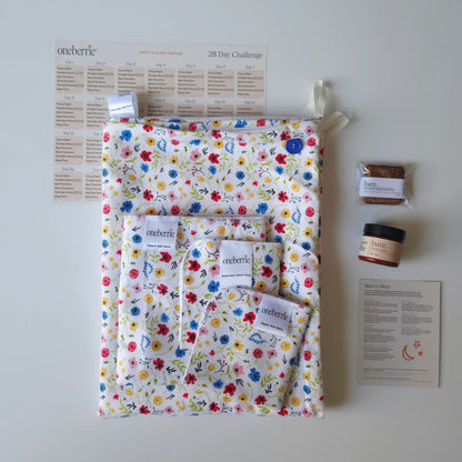 A Bath to Bed Complete set by OneBerrie, featuring the wild pattern with small colourful wildflowers, a matching bath swaddle, a washcloth, a wipe, a 2oz Bare. lotion and 30g Bare. Shampoo Wash bar, a 28-day challenge tracker sheet, and an instruction card on a light gray background.