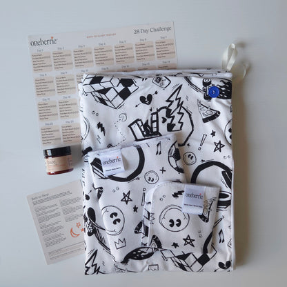 A Bath Bundle set by OneBerrie, featuring  Cool Dudes retro pattern with black designs on a white background, a matching bath swaddle, a washcloth, a 2oz Bare. Lotion, a 28-day challenge tracker sheet, and an instruction card on a light gray background