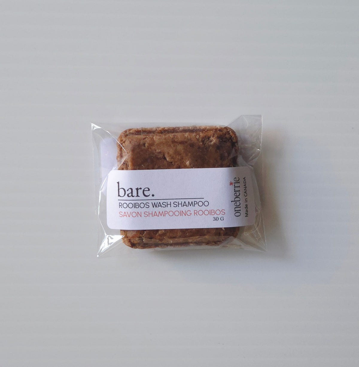 A packaged bar of Oneberrie Bare. rooibos wash shampoo from the on a light gray background.
