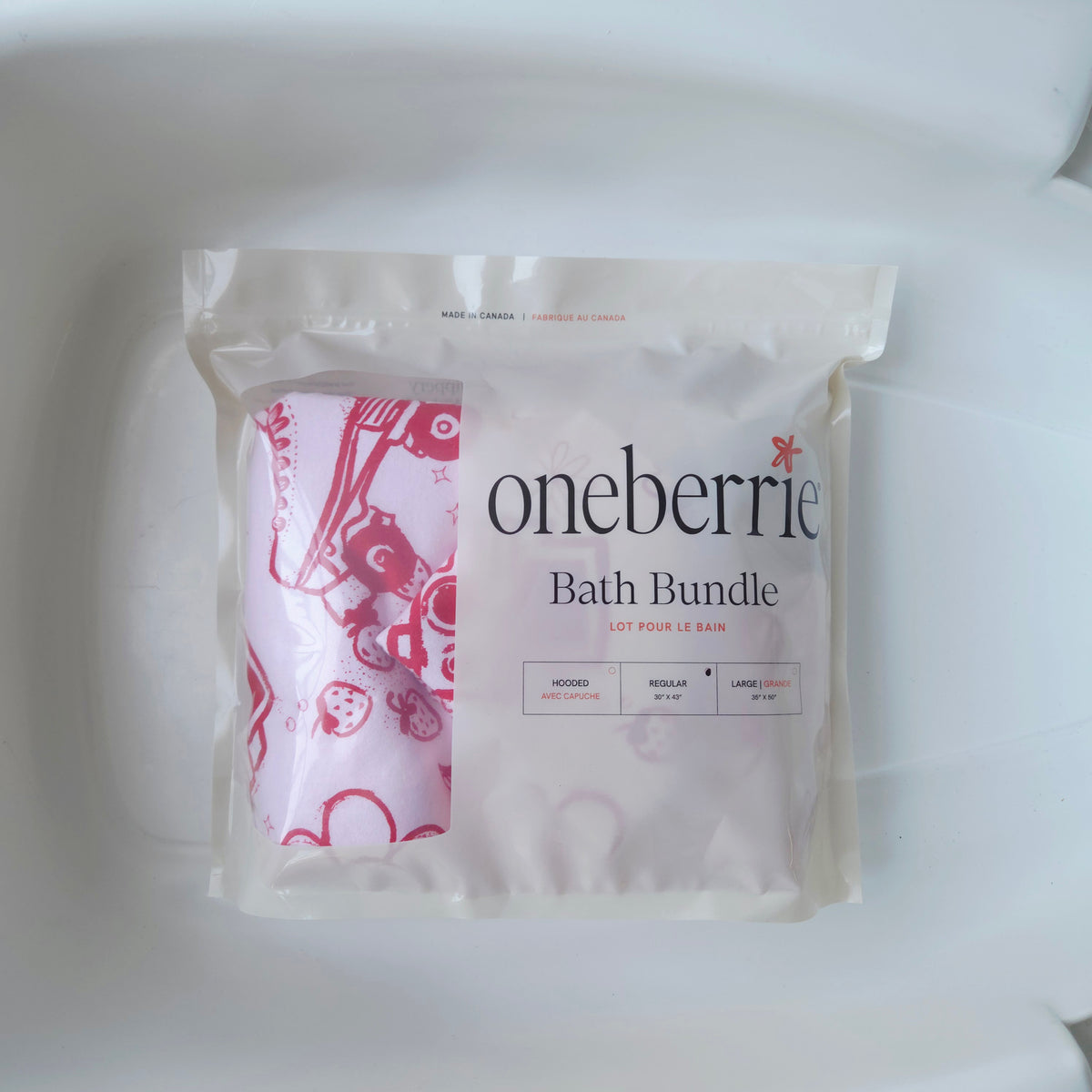 Oneberrie Bath Bundle in a clear resealable pouch, showing a pink and white patterned bath towel and a folded hands free towel inside.