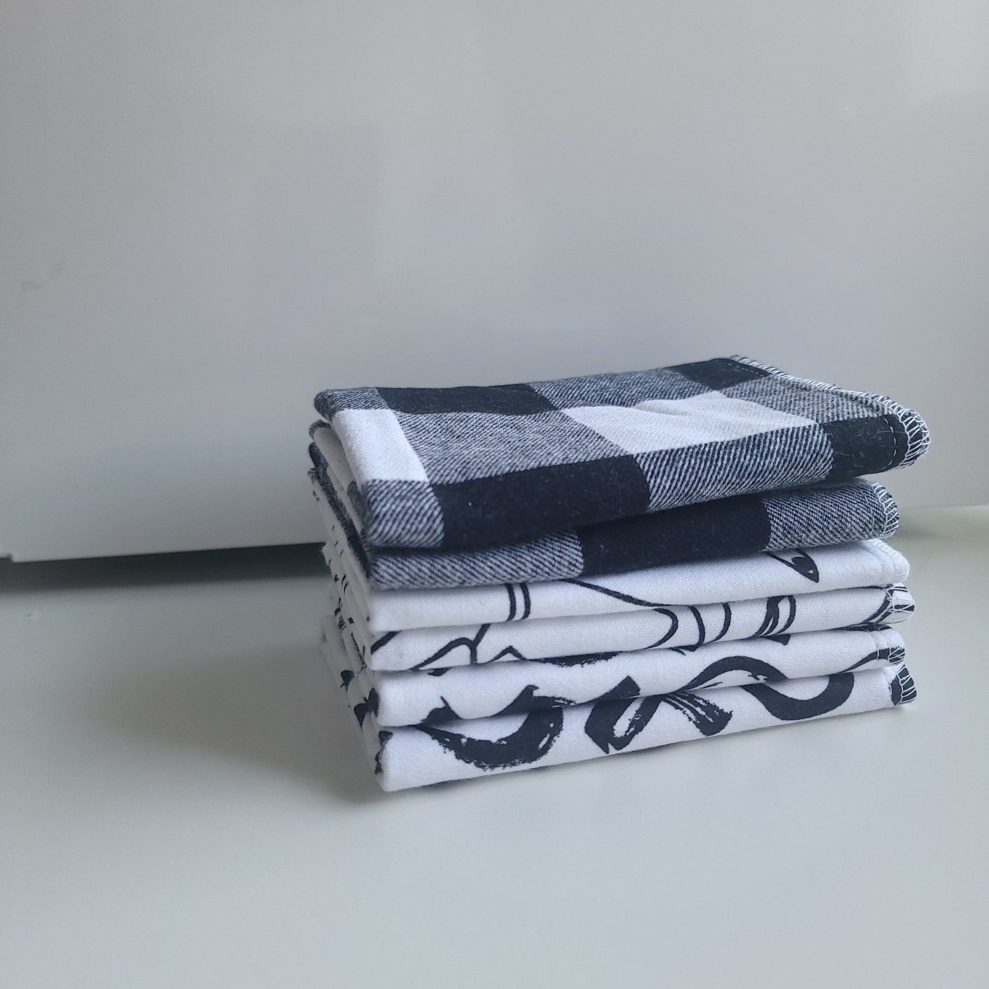 A set of cloth wipes with black and white patterns, displayed both folded and unfolded.