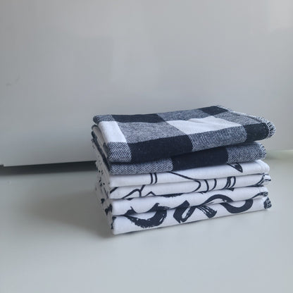 A set of cloth wipes with black and white patterns, displayed both folded and unfolded.