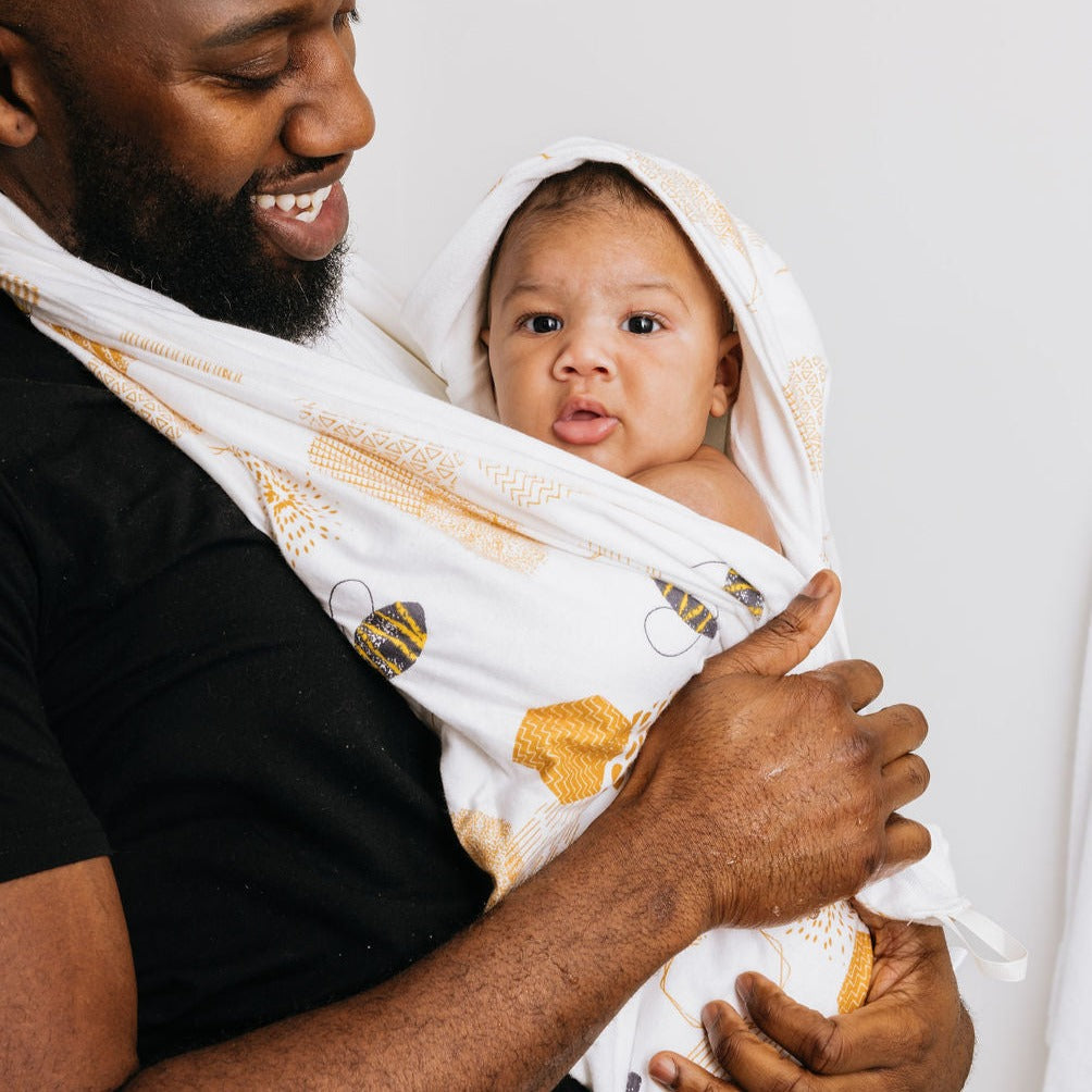 Smiling dad holding his baby wrapped and hooded in the honeycomb print Oneberrie towel