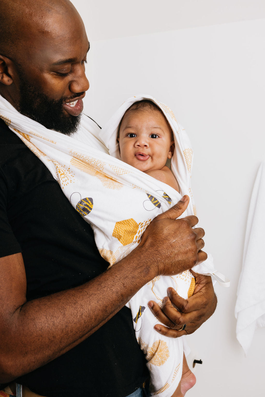 Dad looking down at his baby with the Oneberrie towel clasped around his neck. Baby is looking straight at you as if he was saying something.
