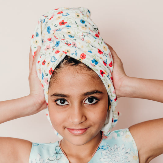 Young girl wearing a wildflower mini hair wrap holding her head in her hands