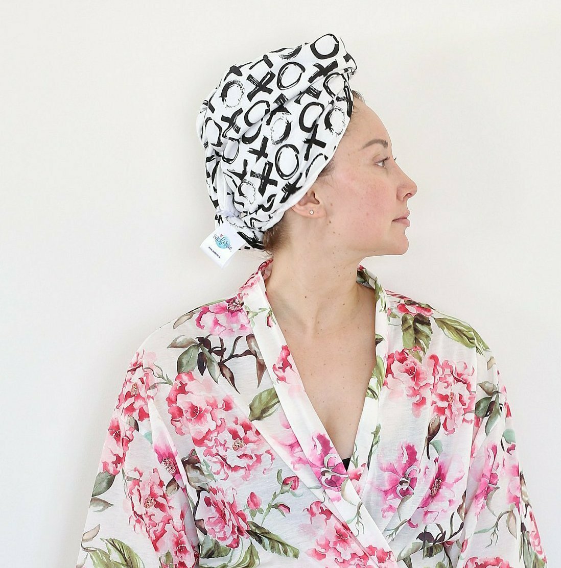 Woman in a floral robe wearing an Oneberrie Hair Wrap Towel in bold black brushstroke XO print, side profile