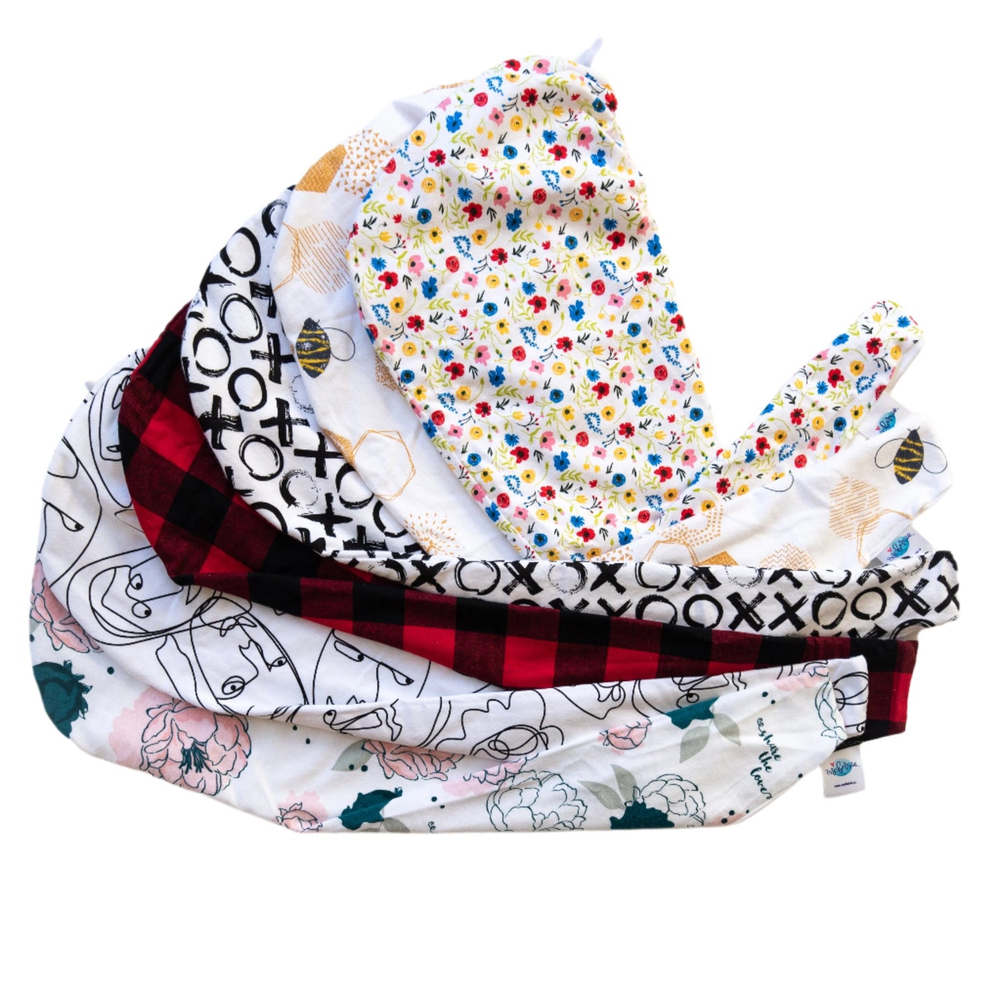 Flat lay of multiple Oneberrie Hair Wrap Towels in assorted prints fanned out on a white background