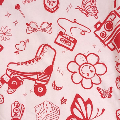 Close-up fabric detail of Oneberrie retro girl print — rollerskates, butterflies, cupcakes, cassette tapes and flowers on a pink background