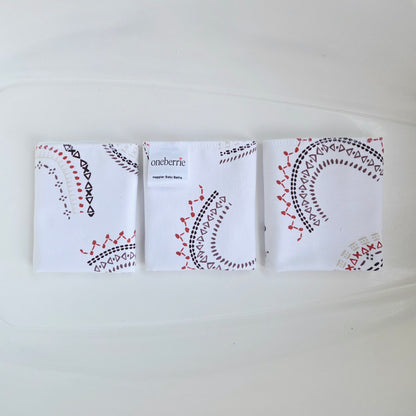 Three folded washcloths arranged side by side on a white background. Each washcloth has a decorative black and red embroidered-style geometric pattern, and the center pouch shows the brand name 'Oneberrie' printed on it
