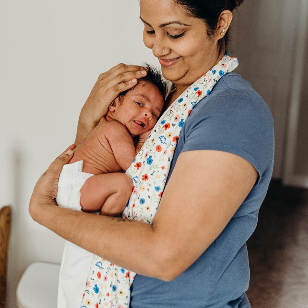 Mother is holding her newborn baby against her chest while the wild towel is suspended between her and the baby. 