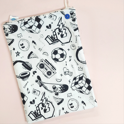 A soft baby towel with a black retro boy pattern which includes a skull, soccer ball, cassette player, skateboard and rubix cube.