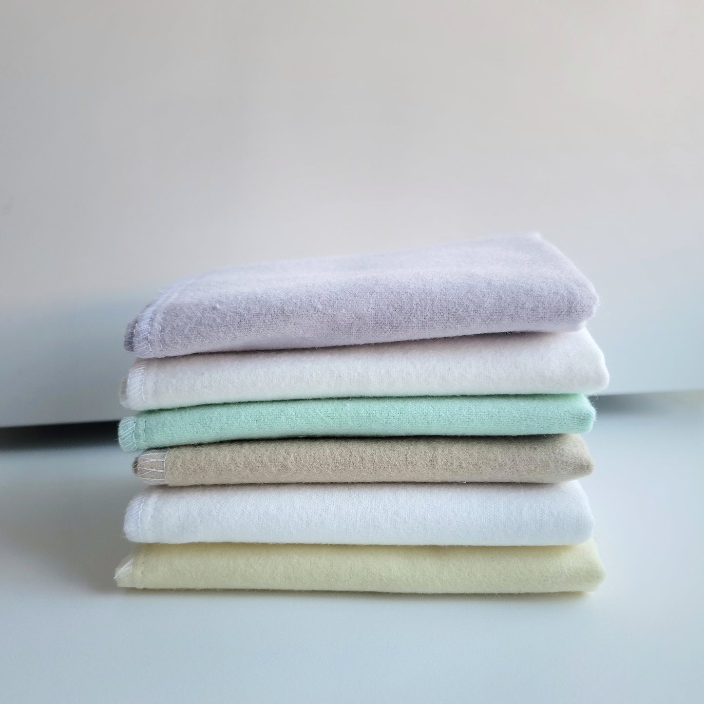 Solid stack of cloth wipes. Lavender, white, butter yellow and cappuccino, displayed folded