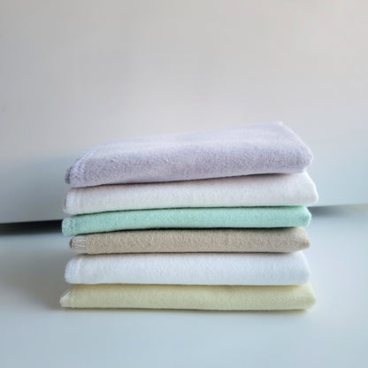 Solid stack of cloth wipes. Lavender, white, butter yellow and cappuccino, displayed folded