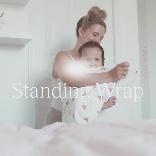 Mom wrapping small girl in a towel and she looks in the mirror. 